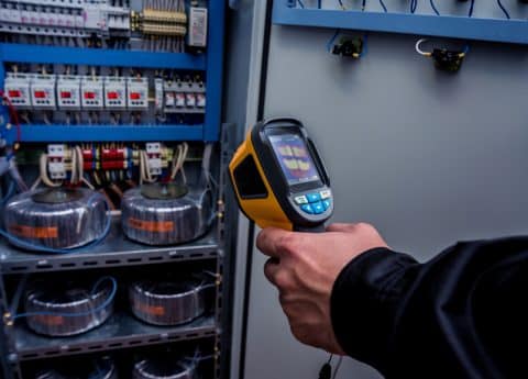 Technician use infrared thermal imaging camera to check temperature at fuse-box.